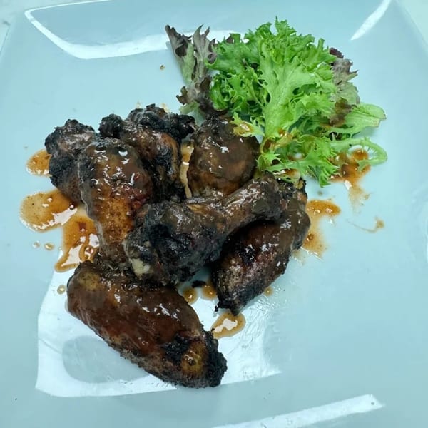Jerk chicken wings with a side of fresh green lettuce on a light blue plate.