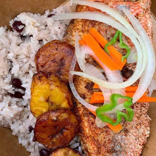 A Jamaican dish with rice and peas, fried plantains, and escovitch fish topped with vegetables.